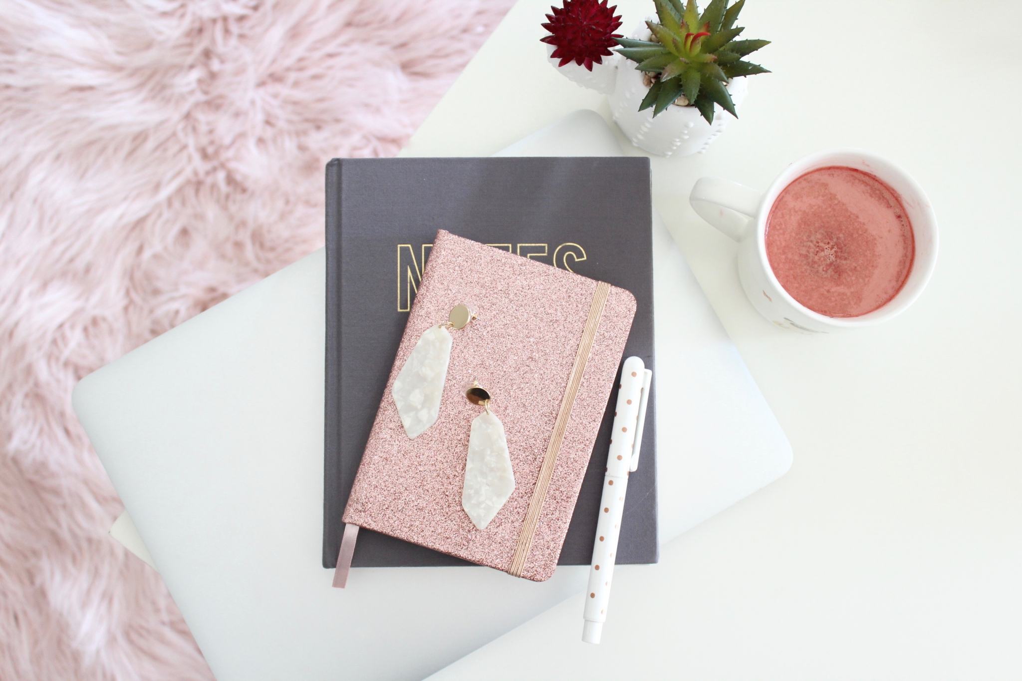 A rose gold stress diary on a white fur background