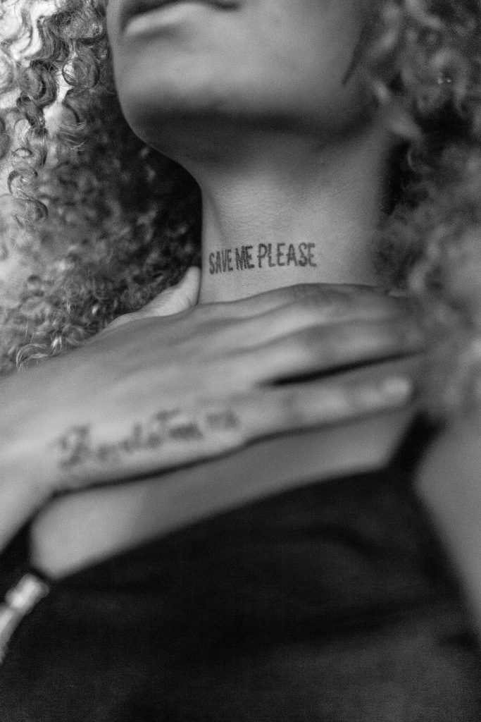 A woman with the words save me please tattooed on her neck.